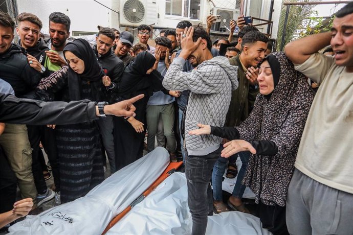 Archivo - Un grupo de palestinos junto a los cadáveres de varios muertos en bombardeos del Ejército de Israel contra Rafá, en el sur de la Franja de Gaza (archivo)