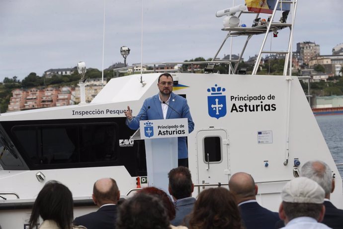 En la imagen, el presidente del Principado, Adrián Barbón, durante su intervención en la presentación de la nueva patrullera de inspección pesquera 'Ría del Eo', con la embarcación al fondo, en el puerto de Castropol.
