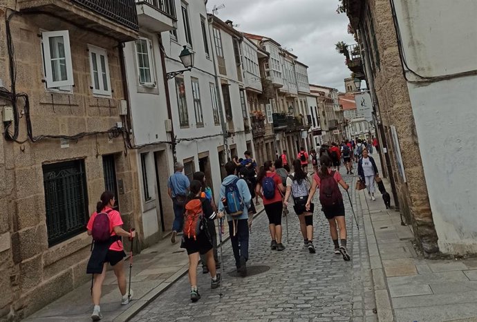Peregrinos bajan por el medio de la Rúa de San Pedro, en Santiago de Compostela