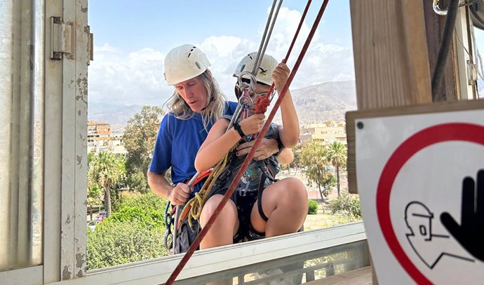 Un usuario del campamento de Inturjoven en Aguadulce realiza una actividad de escalada guiado por un monitor.