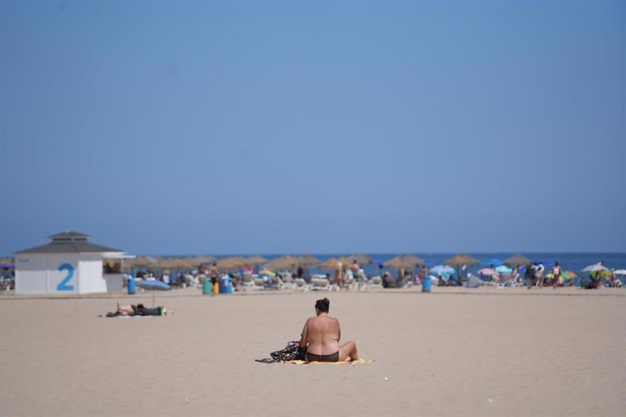 Archivo - Una persona sentada en una toalla en la playa durante la cuarta ola de calor del verano, a 22 de agosto de 2023, en Valencia, Comunidad Valenciana (España). 
