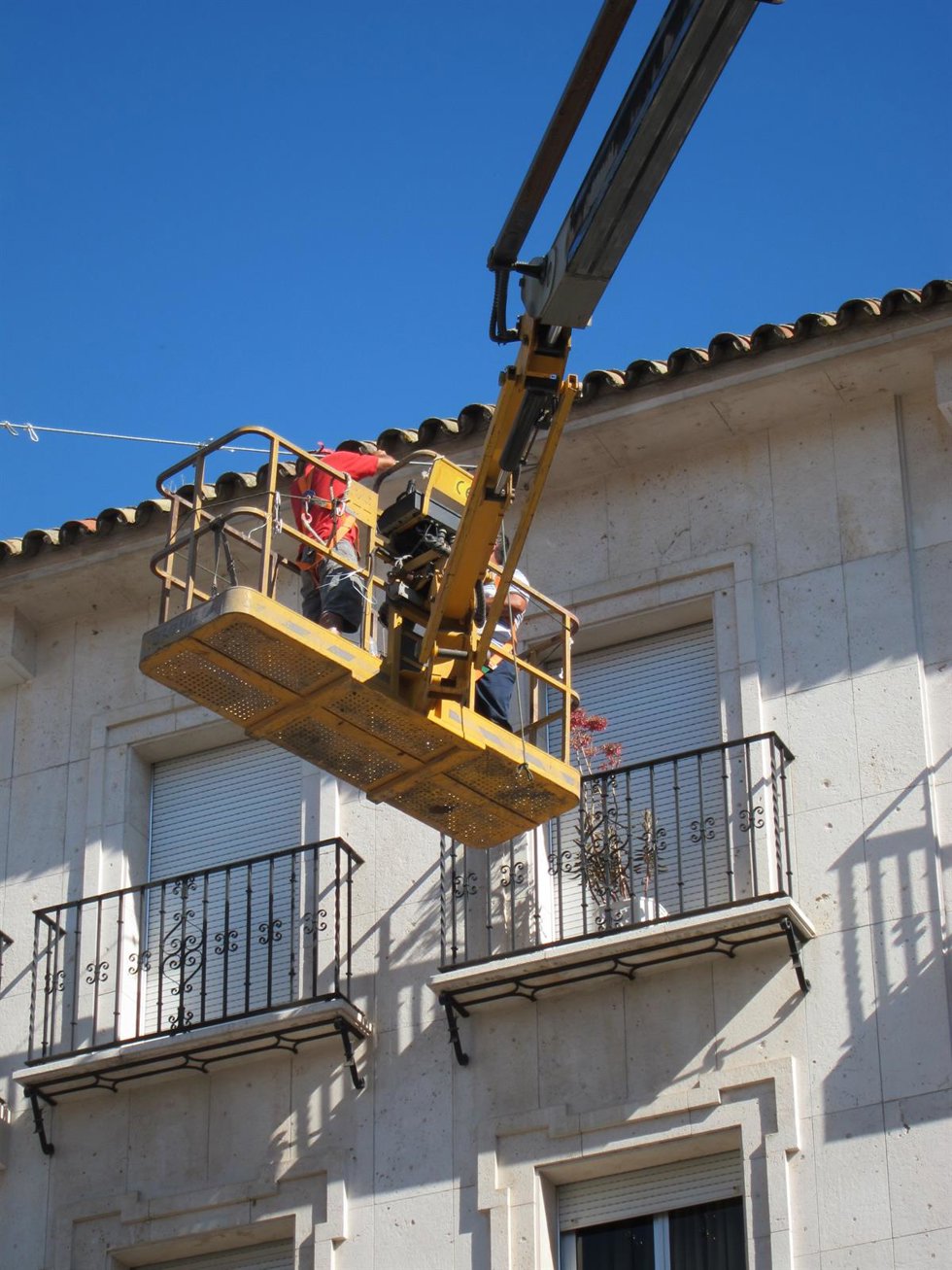 Archivo - Dos operarios trabajan en altura expuestos al sol