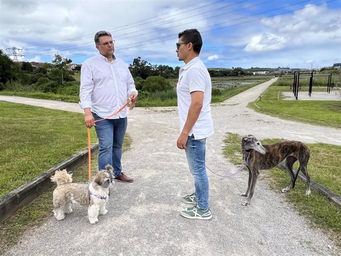 Dos perros con sus propietarios de paseo por Astillero