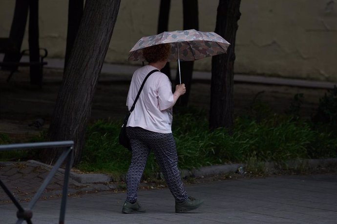 Una mujer se protege de la lluvia con un paraguas, a 8 de junio de 2024, en Madrid (España)