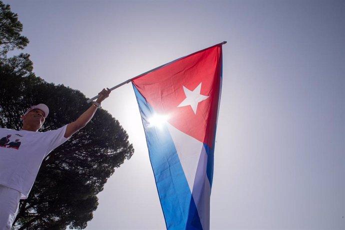 Archivo - Un hombre sostiene una bandera de Cuba en una protesta por la visita del presidente cubano, Miguel Díaz-Canel, a El Vaticano.