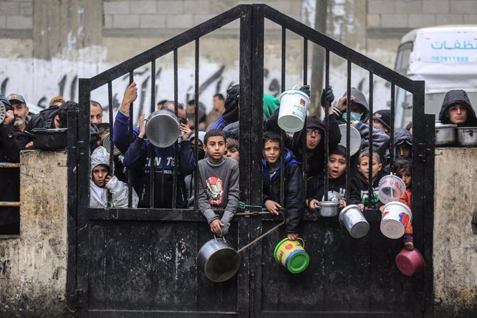 Archivo - Niños desplazados palestinos esperan recibir comida en Rafá, en la Franja de Gaza