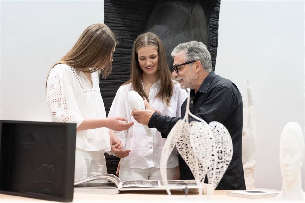 La Princesa Leonor (c) y la Infanta Sofía (i) escuchan al escultor Juame Plensa (d) durante una visita a su taller, a 9 de julio de 2024, en Sant Feliu de Llobregat (Barcelona)