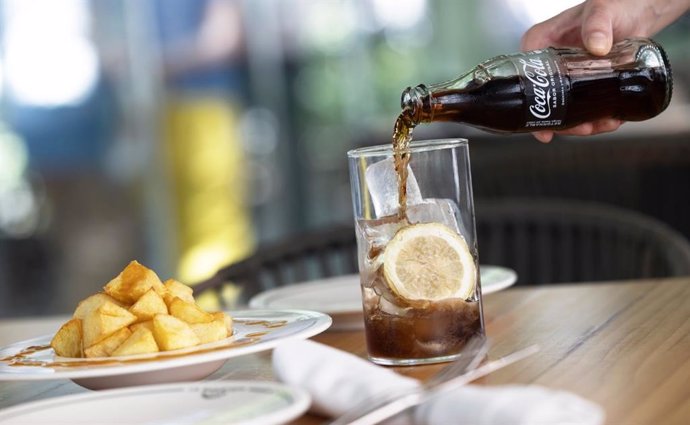 Refresco de Coca-Cola en botella de vidrio y con aperitivo