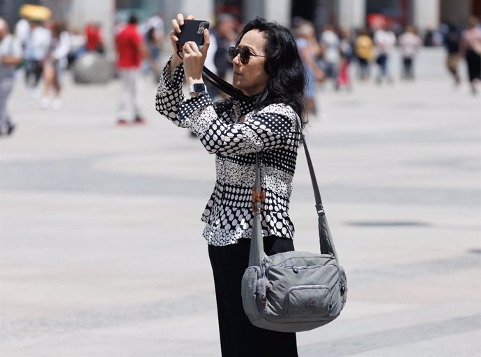 Archivo - Una turista toma fotografías en la Puerta del Sol, a 1 de junio de 2023, en Madrid (España). 