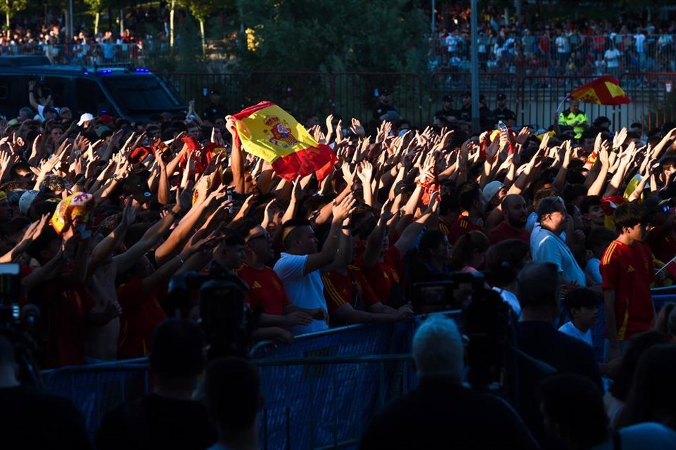Decenas de personas celebran la victoria en el partido de semifinales de la Eurocopa entre España y Francia visto desde una pantalla gigante.
