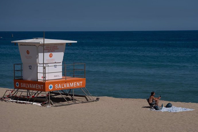 Archivo - Un hombre en la playa del Bogatell, cerca de una cabina de socorristas, a 15 de abril de 2024, en Barcelona, Catalunya (España)