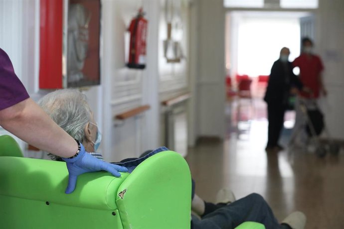 Archivo - Una gerocultura ayuda en el traslado a un residente en una residencia.