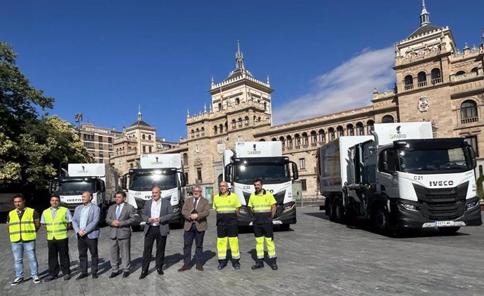 Autoridades y operarios del Servicio de Limpieza, ante los cuatro nuevos camiones y el edificio de la Academia de Caballería.