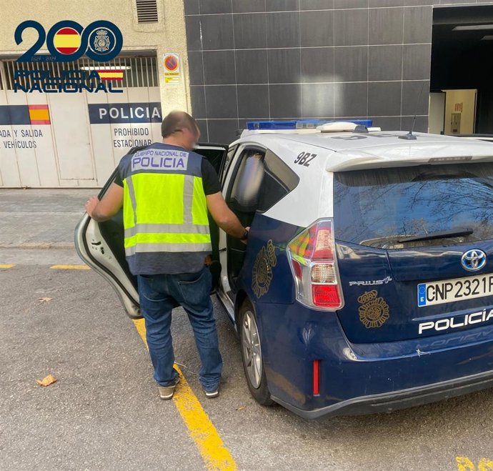 Un agente de la Policía Nacional junto a un vehículo oficial.