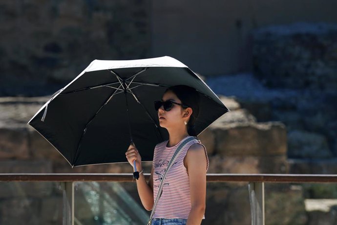 Una mujer se protege del sol con un paraguas, a 12 de julio de 2024, en Málaga.