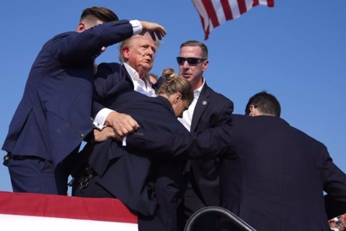 This video screenshot shows former U.S. President Donald Trump being helped off the stage at a rally in Butler, Pennsylvania of the United States after what sounded like gunshots rang out through the crowd, July 13, 2024.