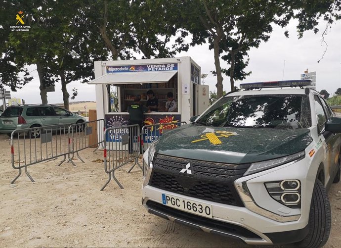 Imagen de un coche de la Guardia Civil junto un puesto de venta de petardos.