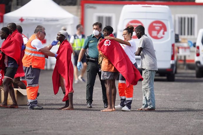 Archivo - Trabajadores de la Cruz Roja tapan con mantas a un grupo de migrantes llegados a las costas canarias