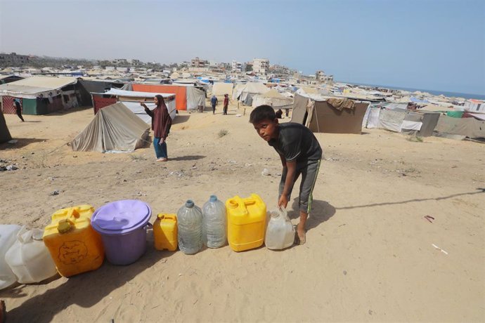 Un niño palestinojunto a varios bidones cerca de un punto de recogida de agua en Al Zauaida, en el centro de la  Franja de Gaza, en el marco de la ofensiva militar de Israel contra el enclave (archivo)