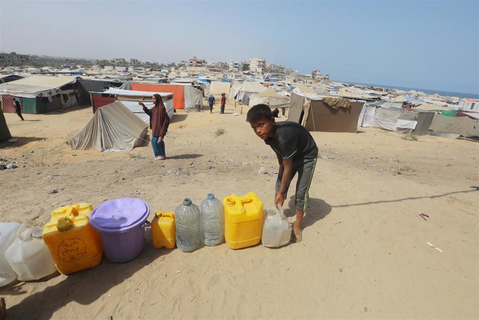 Un niño palestinojunto a varios bidones cerca de un punto de recogida de agua en Al Zauaida, en el centro de la Franja de Gaza, en el marco de la ofensiva militar de Israel contra el enclave (archivo)