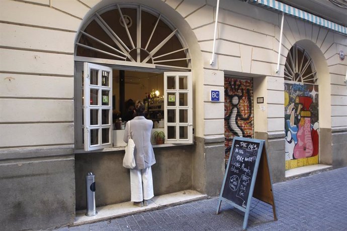 Archivo - Una mujer en la ventana de una cafetería en Palma.