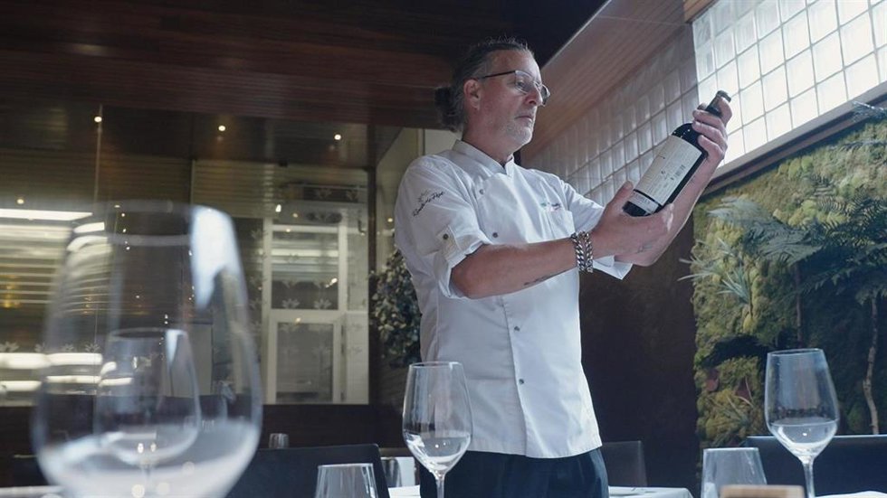 El chef Ginés Nicolás Fernández del restaurante El Rincón de Pepe sostiene una botella del vino de Bodegas Luzón Por Ti