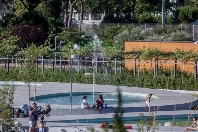 Varias personas se refrescan durante la llegada de la primera ola de calor, en el parque del Canal de Isabel II 