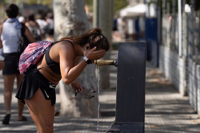 Una persona es refresca en una font de Barcelona