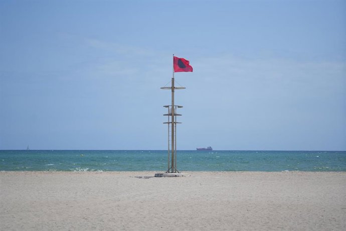 Bandera roja durante las labores de limpieza en la playa del Saler por el vertido,