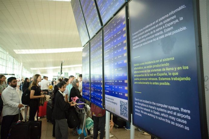 Colas de pasajeros ante una pantalla que avisa de la incidencia informática en el Aeropuerto de Barcelona-El Prat.