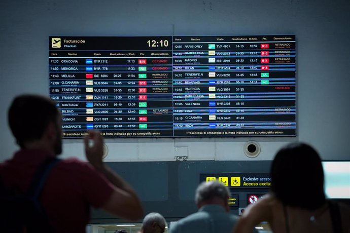 Pasajeros en el aeropuerto de Sevilla atentos a la información sobre los vuelos que aparece en las pantallas.