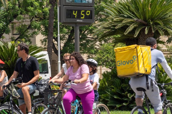 Un termómetro marca 45 grados a las 14:00 de la tarde junto a un trabajador de Glovo en bicicleta, a 19 de julio de 2024, en Sevilla, Andalucía (España). 