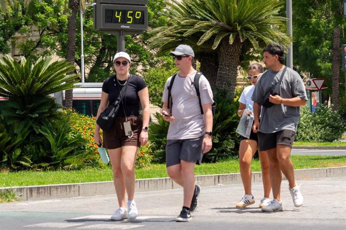 Un termómetro marca 45 grados a las 14:00 de la tarde junto a unos turistas paseando, a 19 de julio de 2024, en Sevilla, Andalucía (España). 