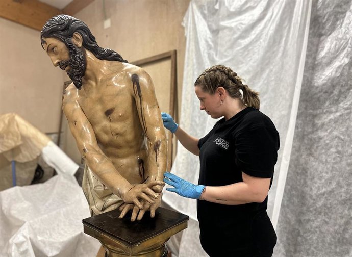 Una de las profesionales del Centro de Conservación y Restauración de la Fundación Edades del Hombre limpia una de las piezas extraídas de la Vera Cruz, 'El señor atado a la columna', de Gregorio Fernández.