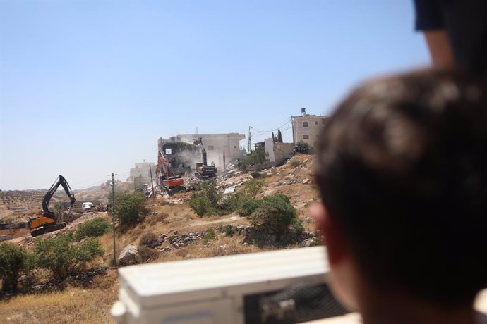 July 11, 2024, Hebron, West Bank, Palestinian Territory: Palestinians watch as Israeli machinery, guarded by Israeli forces, demolishes a Palestinian house near Hebron, in the Israeli-occupied West Bank, July 11, 2024