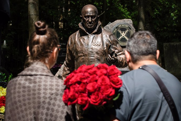 Archivo - June 1, 2024, St. Petersburg, Russia: People stand with a bouquet of roses near a sculpture of Russian mercenary leader Yevgeny Prigozhin installed on his grave during celebrations of his birthday to honor his memory at Porokhovskoye Cemetery in