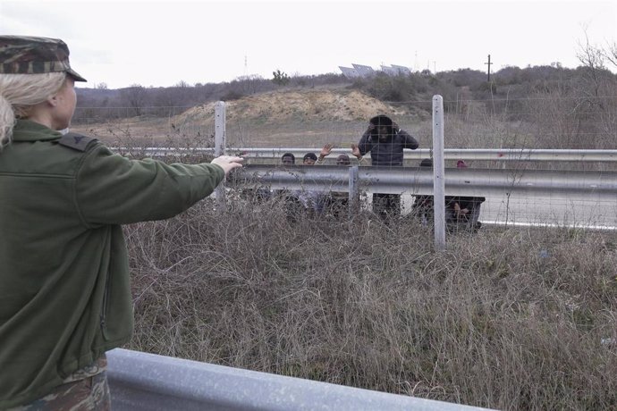 Archivo - Una guardia fronteriza de Grecia señala a un grupo de migrantes en la frontera con Turquía