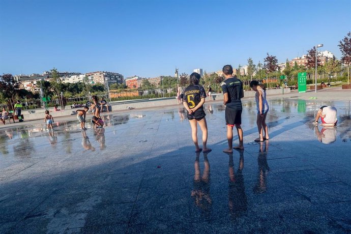 Varias personas se refrescan en el parque del Canal de Isabel II