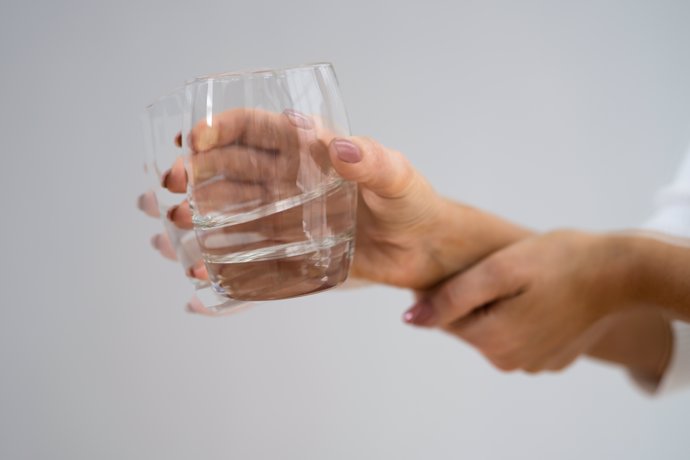 Mujer sujera un vaso para tomar la medicación