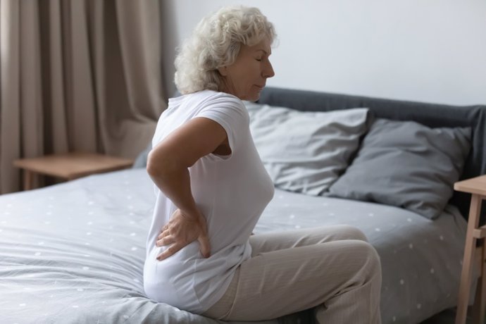 Archivo - Mujer en la habitación con dolor en la espalda. Fibronialgia. Dolor crónico.