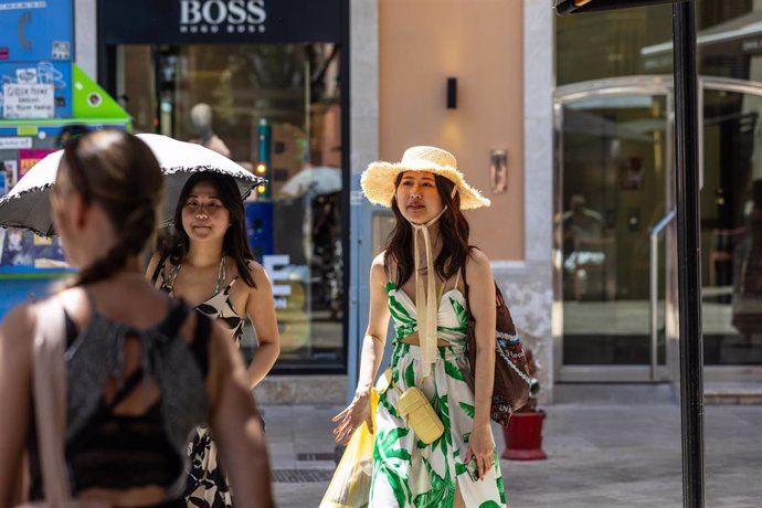 Archivo - Unas turistas se protegen del sol y el calor con sombrilla y sombrero.