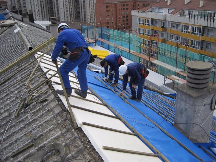 Varios trabajadores en una obra sobre un tejado.