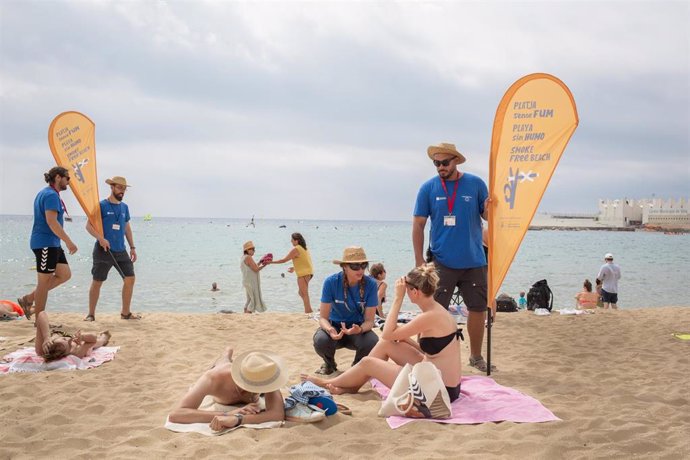 Archivo - Dos informadores conversan de la nueva prohibición de fumar con bañistas, en la playa del Bogatell, a 25 de julio de 2022, en Barcelona, Catalunya (España). El pleno del Ayuntamiento de Barcelona ha aprobado definitivamente la prohibición de fum