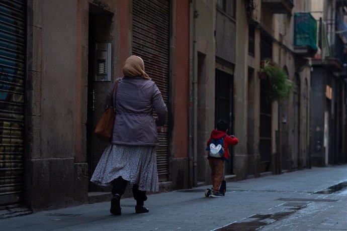 Archivo - Una mujer camina por una calle en Barcelona