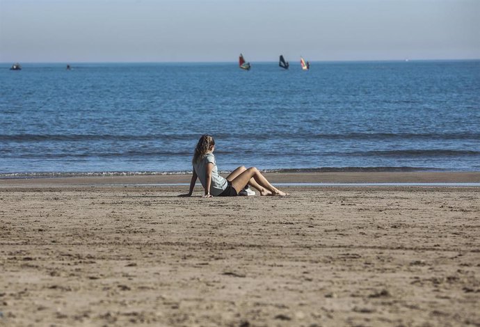 Archivo - Una mujer sentada en la arena de la playa de la Malva-rosa (archivo)