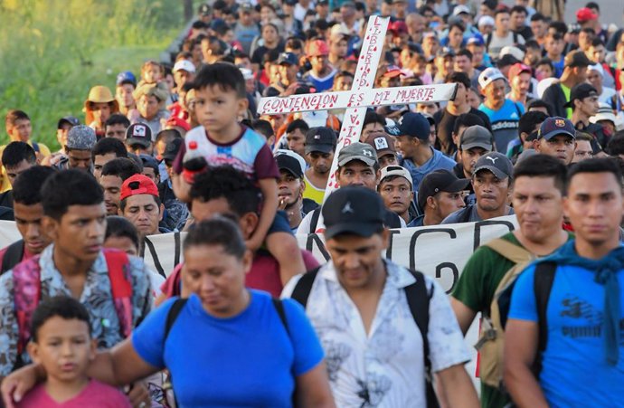 Archivo - 31 October 2023, Mexico, Chiapas: People carry a cross and continue north along the side of a highway hoping to cross Mexico and enter the United States.