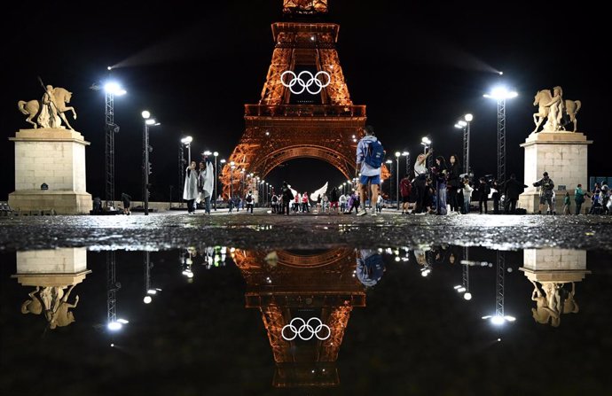 27 July 2024, France, Paris: The illuminated Eiffel Tower with the Olympic rings is reflected on a puddle after the opening ceremony of the Paris 2024 Olympic Games. Photo: Sven Hoppe/dpa