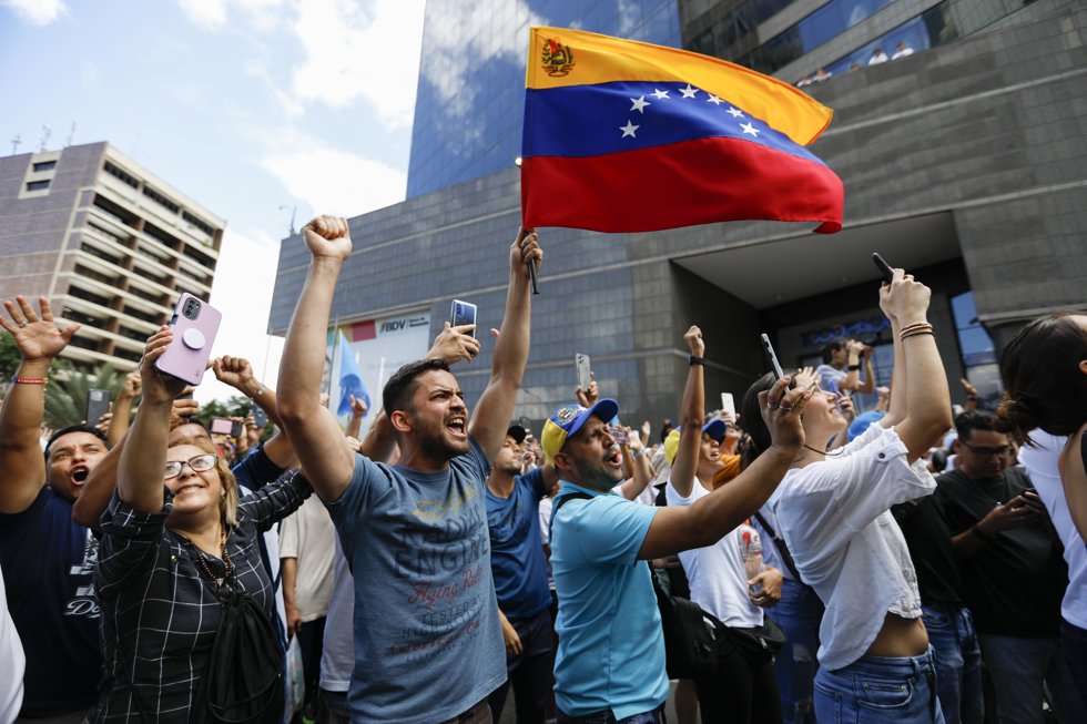 30 July 2024, Venezuela, Caracas: Venezuelans wave flags and shout slogans in support of opposition leaders Machado and Gonzalez Urrutia during a demonstration against the official results of the presidential election.