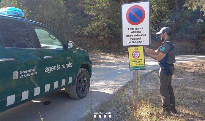 Un agente de Agents Rurals coloca una señal para restringir el acceso a una zona en elevado riesgo de incendio