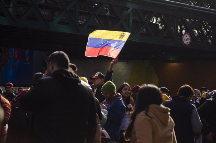 Un hombre sostiene una bandera venezolana frente a la Embajada de Venezuela en Buenos Aires durante las elecciones presidenciales